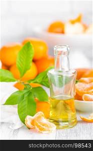 Tangerines with leaves and bottle of essential citrus oil on a white background