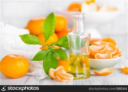 Tangerines with leaves and bottle of essential citrus oil on a white background