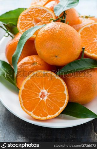 Tangerines with leaves on plate, selective focus, closeup
