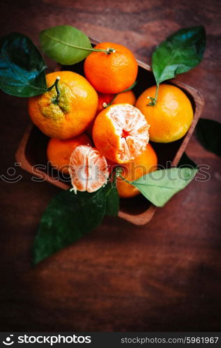 Tangerines with leaves on rustic wooden background