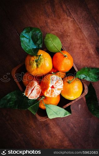 Tangerines with leaves on rustic wooden background