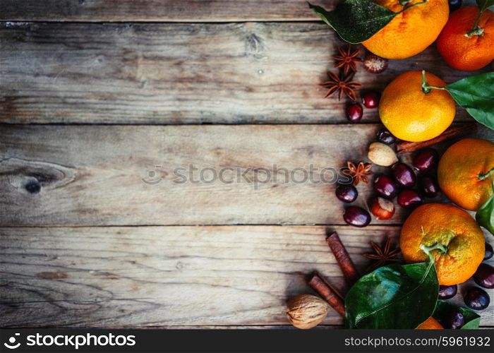 Tangerines with nuts,cranberries and cinnamon on rustic wooden background