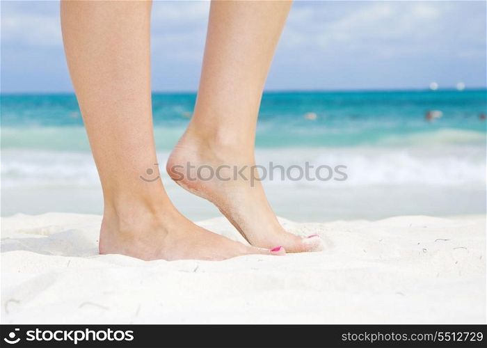 tanned legs of woman standing on the beach