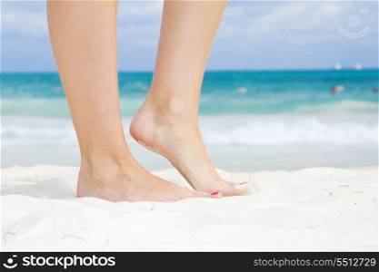 tanned legs of woman standing on the beach