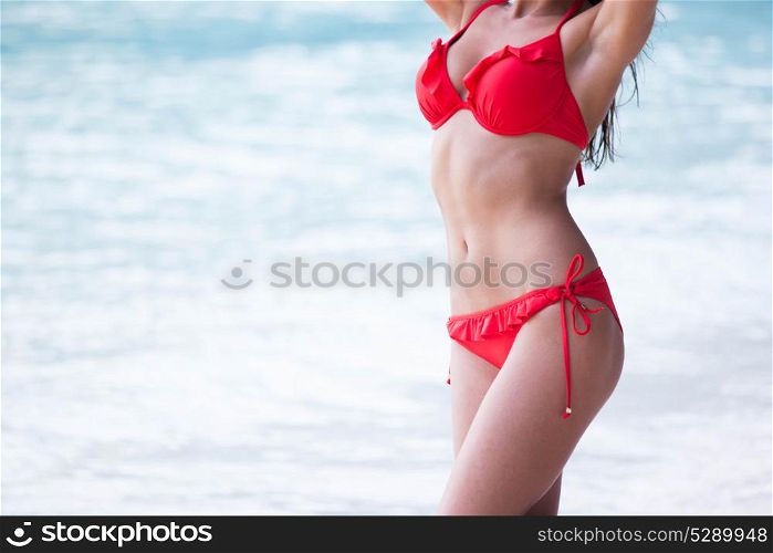 Tanned woman body in red bikini. Tanned woman body in red bikini, blue sea water in background