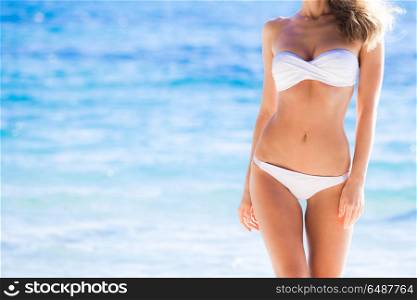 Tanned woman body in white bikini. Tanned woman body in white bikini, blue sea water in background