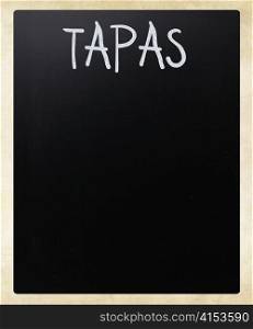 ""Tapas" handwritten with white chalk on a blackboard"