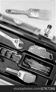 Tape measure, wrench, fasteners, and box cutter arranged in a tool box