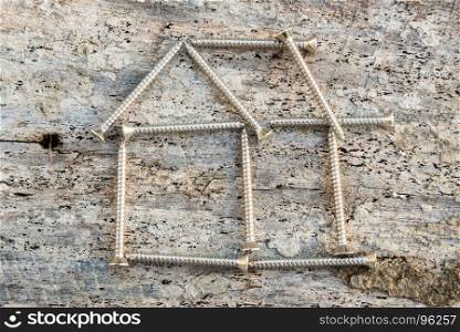Tapping screws house on wood background, Dream house success concept
