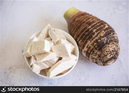 Taro root with slice cubes on bowl and table background, Fresh raw organic taro root ready to cook