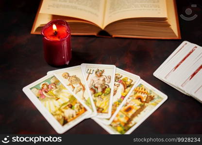 Tarot cards with candlelight and book on the darkness background,Halloween and future reading concept.