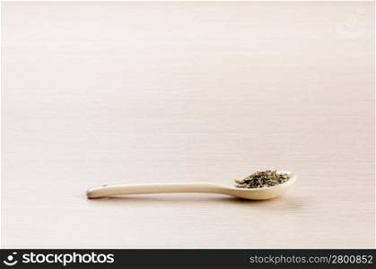 Tarragon in a spoon over a blured wooden background with copy space