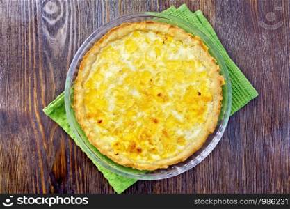 Tart with cheese, leek and sour and egg cream in a glass shape on a green kitchen towel on the background of wooden boards