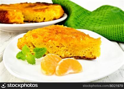 Tart with mandarin, mint, tangerine slices in white plate, a towel on the background light wooden boards