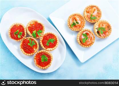 tartalets with salmon fish and caviar on a table