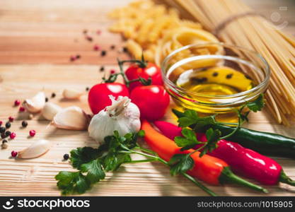 Tasty appetizing italian spaghetti pasta ingredients for kitchen cuisine with tomato, cheese parmesan, olive oil, fettuccine and basil on wooden brown table. Food Italian recipe homemade. Top view