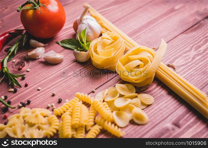 Tasty appetizing italian spaghetti pasta ingredients for kitchen cuisine with tomato, cheese parmesan, olive oil, fettuccine and basil on wooden brown table. Food Italian recipe homemade. Top view