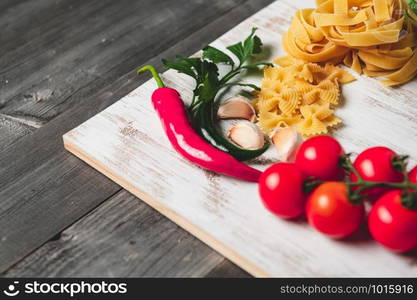 Tasty appetizing italian spaghetti pasta ingredients for kitchen cuisine with tomato, cheese parmesan, olive oil, fettuccine and basil on wooden brown table. Food Italian recipe homemade. Top view