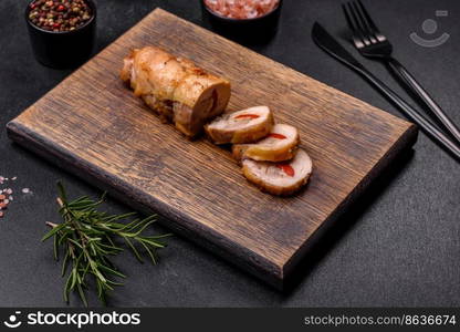 Tasty baked meat roll of chicken meat, sweet pepper with spices and herbs on a wooden cutting board. Tasty baked meat roll of chicken meat, sweet pepper with spices and herbs