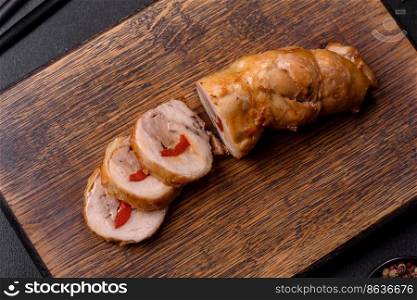 Tasty baked meat roll of chicken meat, sweet pepper with spices and herbs on a wooden cutting board. Tasty baked meat roll of chicken meat, sweet pepper with spices and herbs
