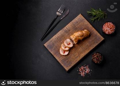 Tasty baked meat roll of chicken meat, sweet pepper with spices and herbs on a wooden cutting board. Tasty baked meat roll of chicken meat, sweet pepper with spices and herbs