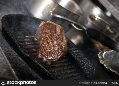 Tasty beef steak grilling in a cast-iron ribbed fry pan