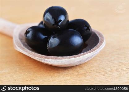 tasty black olive in wooden spoon