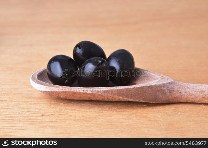 tasty black olive in wooden spoon