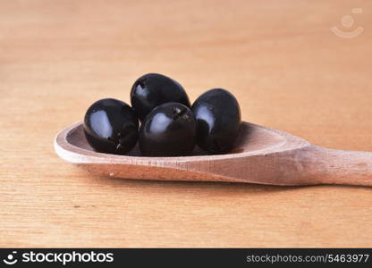 tasty black olive in wooden spoon