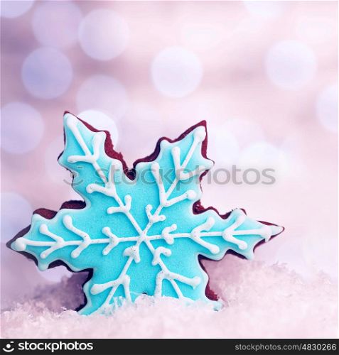 Tasty blue snowflake shaped cookie in snow decoration, traditional Christmas gingerbread, winter holidays dessert