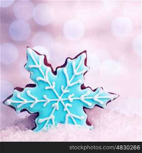 Tasty blue snowflake shaped cookie in snow decoration, traditional Christmas gingerbread, winter holidays dessert
