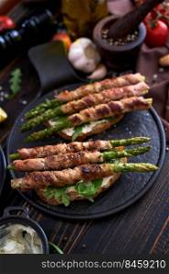 Tasty breakfast - toasts with cream cheese and Asparagus wrapped with bacon and spices on a plate.. Tasty breakfast - toasts with cream cheese and Asparagus wrapped with bacon and spices on a plate
