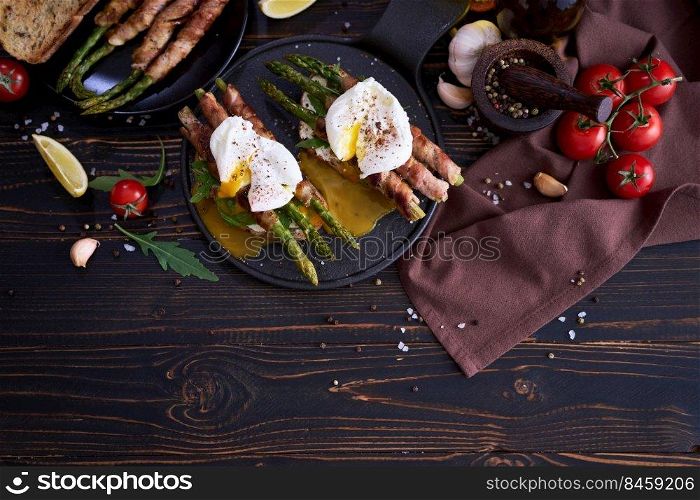 Tasty breakfast - toasts with cream cheese, poached eggs and Asparagus wrapped with bacon and spices on a plate.. Tasty breakfast - toasts with cream cheese, poached eggs and Asparagus wrapped with bacon and spices on a plate
