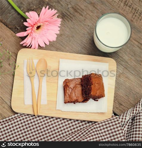 Tasty brownies with glass of milk and flower, retro filter effect