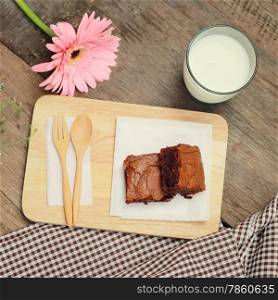 Tasty brownies with glass of milk and flower, retro filter effect