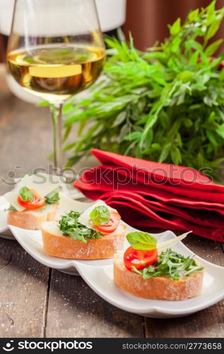 Tasty bruschetta canapes with arugula and tomatoes