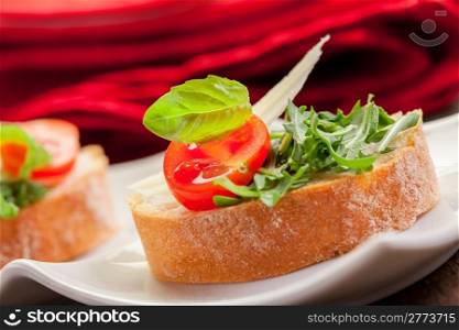 Tasty bruschetta canapes with arugula and tomatoes