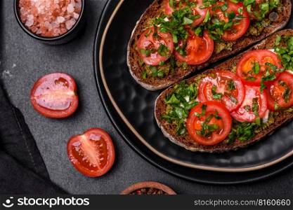 Tasty bruschetta with tomatoes, mozzarella, basil, spices and herbs on a dark concrete background. Tasty bruschetta with tomatoes, mozzarella, basil, spices and herbs
