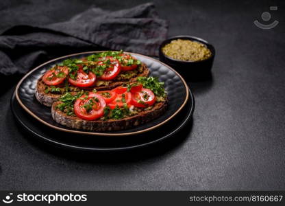 Tasty bruschetta with tomatoes, mozzarella, basil, spices and herbs on a dark concrete background. Tasty bruschetta with tomatoes, mozzarella, basil, spices and herbs