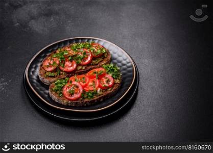 Tasty bruschetta with tomatoes, mozzarella, basil, spices and herbs on a dark concrete background. Tasty bruschetta with tomatoes, mozzarella, basil, spices and herbs
