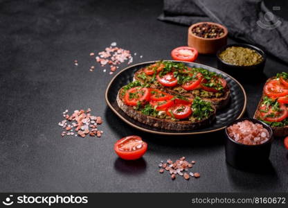 Tasty bruschetta with tomatoes, mozzarella, basil, spices and herbs on a dark concrete background. Tasty bruschetta with tomatoes, mozzarella, basil, spices and herbs