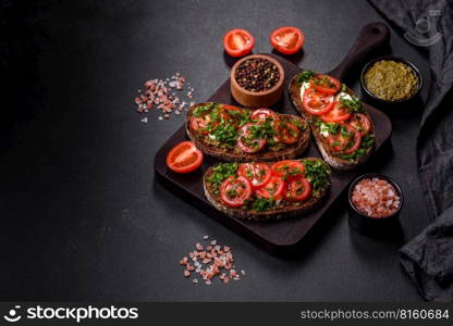 Tasty bruschetta with tomatoes, mozzarella, basil, spices and herbs on a dark concrete background. Tasty bruschetta with tomatoes, mozzarella, basil, spices and herbs