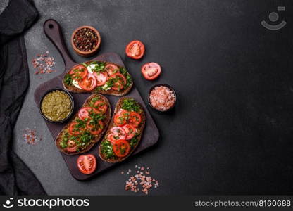 Tasty bruschetta with tomatoes, mozzarella, basil, spices and herbs on a dark concrete background. Tasty bruschetta with tomatoes, mozzarella, basil, spices and herbs