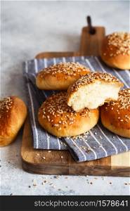 Tasty bun buns with sesame seeds on a wooden board.