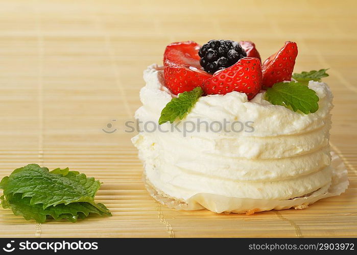 tasty cake with white icing and strawberries on bamboo table cloth