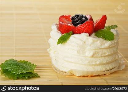 tasty cake with white icing and strawberries on bamboo table cloth
