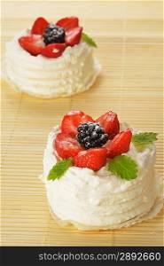 tasty cakes with white icing and strawberries on bamboo table cloth