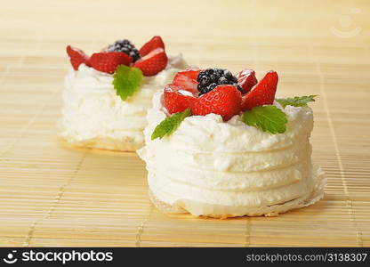 tasty cakes with white icing and strawberries on bamboo table cloth