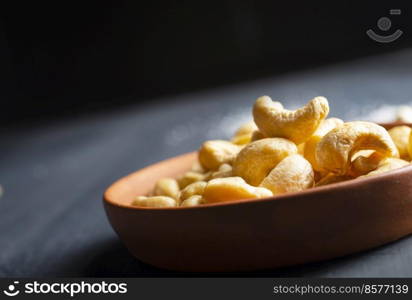 Tasty cashew nuts in bowl on dark table, top view. cashew nuts in bowl on dark table, top view