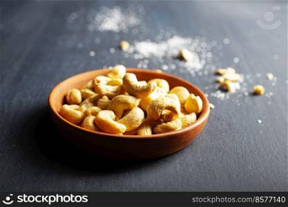 Tasty cashew nuts in bowl on dark table, top view. cashew nuts in bowl on dark table, top view